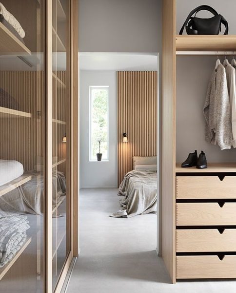 Un dressing à coté d'une chambre à coucher avec des tiroirs et des portes vitrée