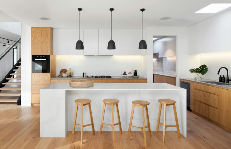 architecte et décoration intérieur Faremoutiers Cuisine moderne avec îlot et chaises en bois, éclairage suspendu et décoration minimaliste.