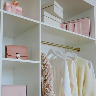 dressing bien rangé-organisation rangement avec des vetements blancs suspendus et des boites de rangement roses